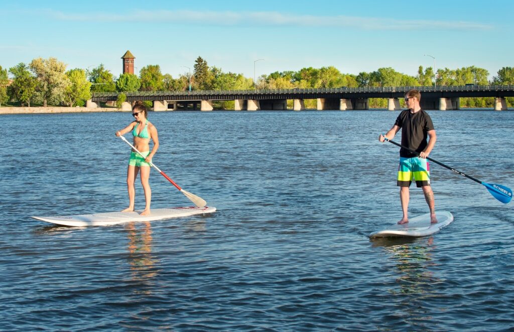 Two people paddleboard on a river in Great Falls, MT