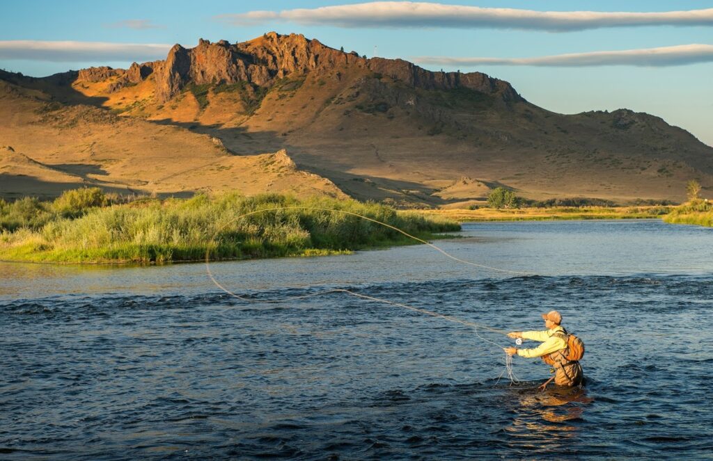 A man wades into the middle of a river in Great Falls, MT to go fly fishing