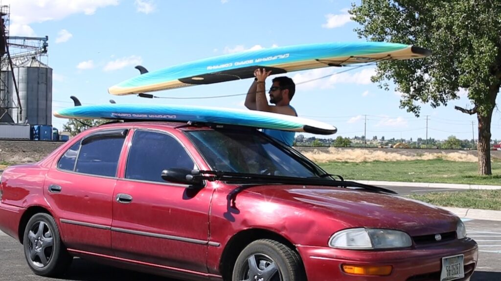 A man loads paddleboards on top of his car