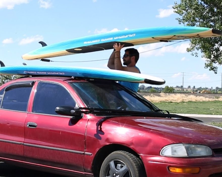 A man loads paddleboards on top of his car