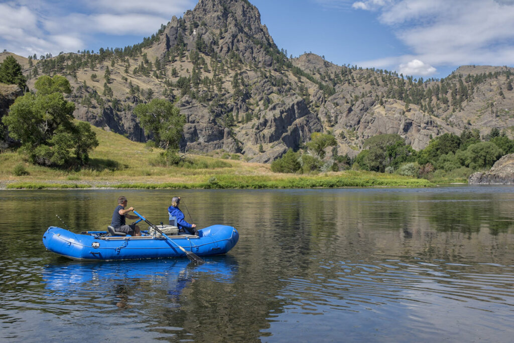 Two people use a boat to navigate down a river in Great Falls, MT